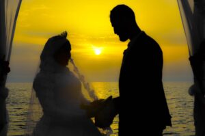 Silhouette of man and woman standing near body of water during sunset
