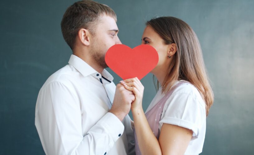 Couple holding red heart obscuring faces