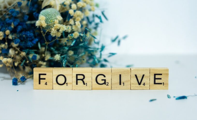 A wooden block that says for give next to a bouquet of flowers